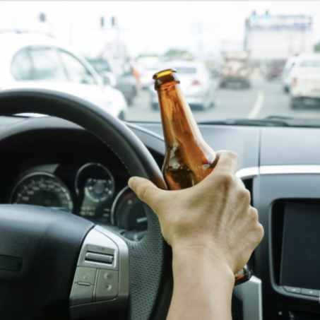 Motorist holding a bottle of alcohol while driving under the influence on Blackout Wednesday.